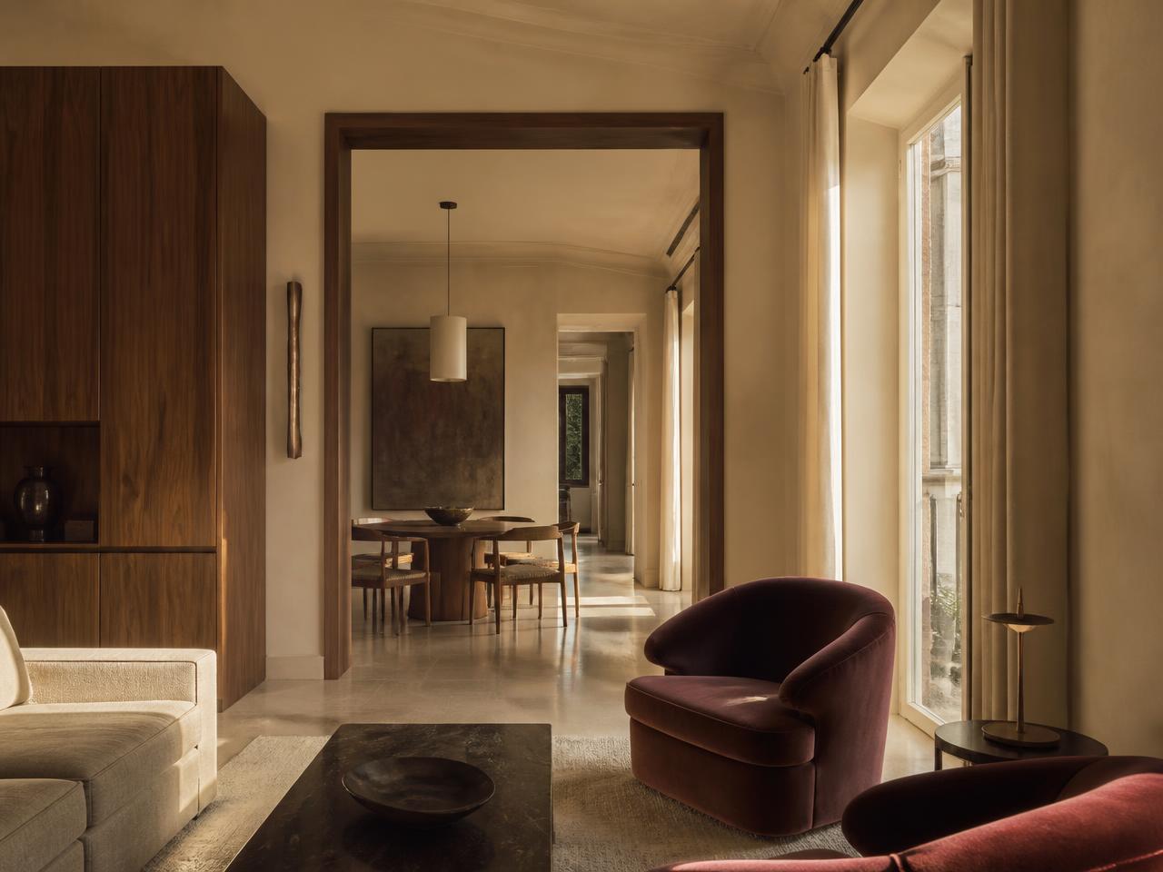 Gerenoveerd interieur met walnoothouten meubels en bordeauxrode fluwelen fauteuil